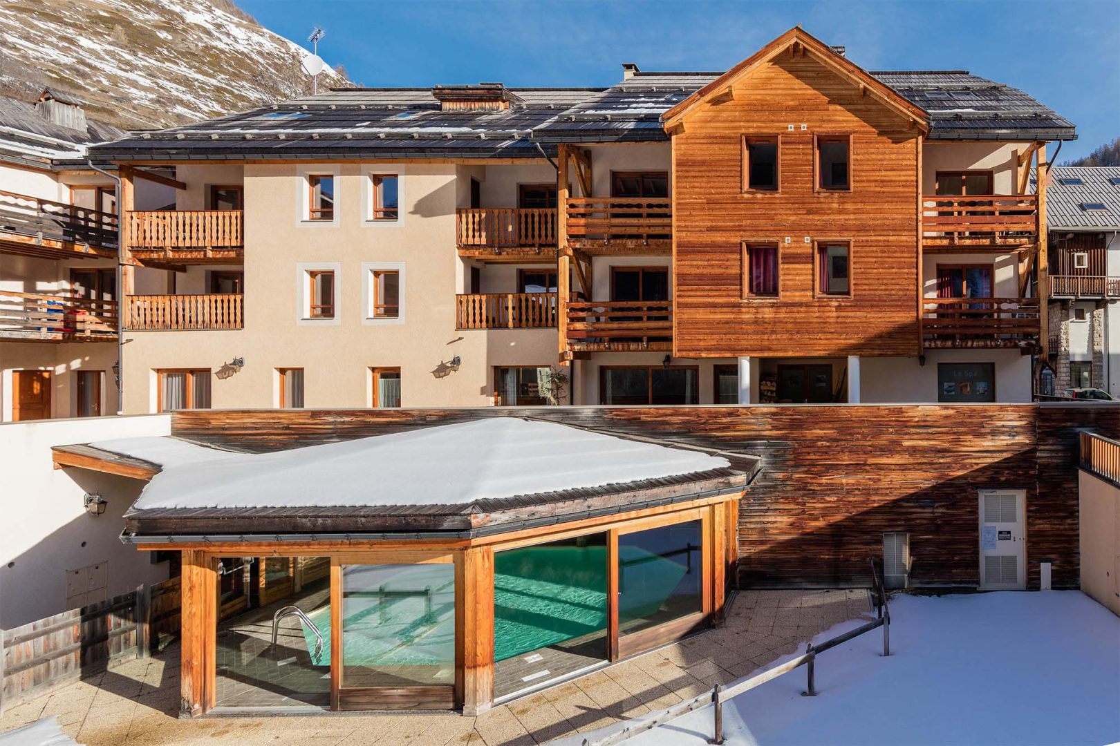 Extérieur de la résidence Les Balcons du Viso à Abriès avec vue sur la nature et piscine.
