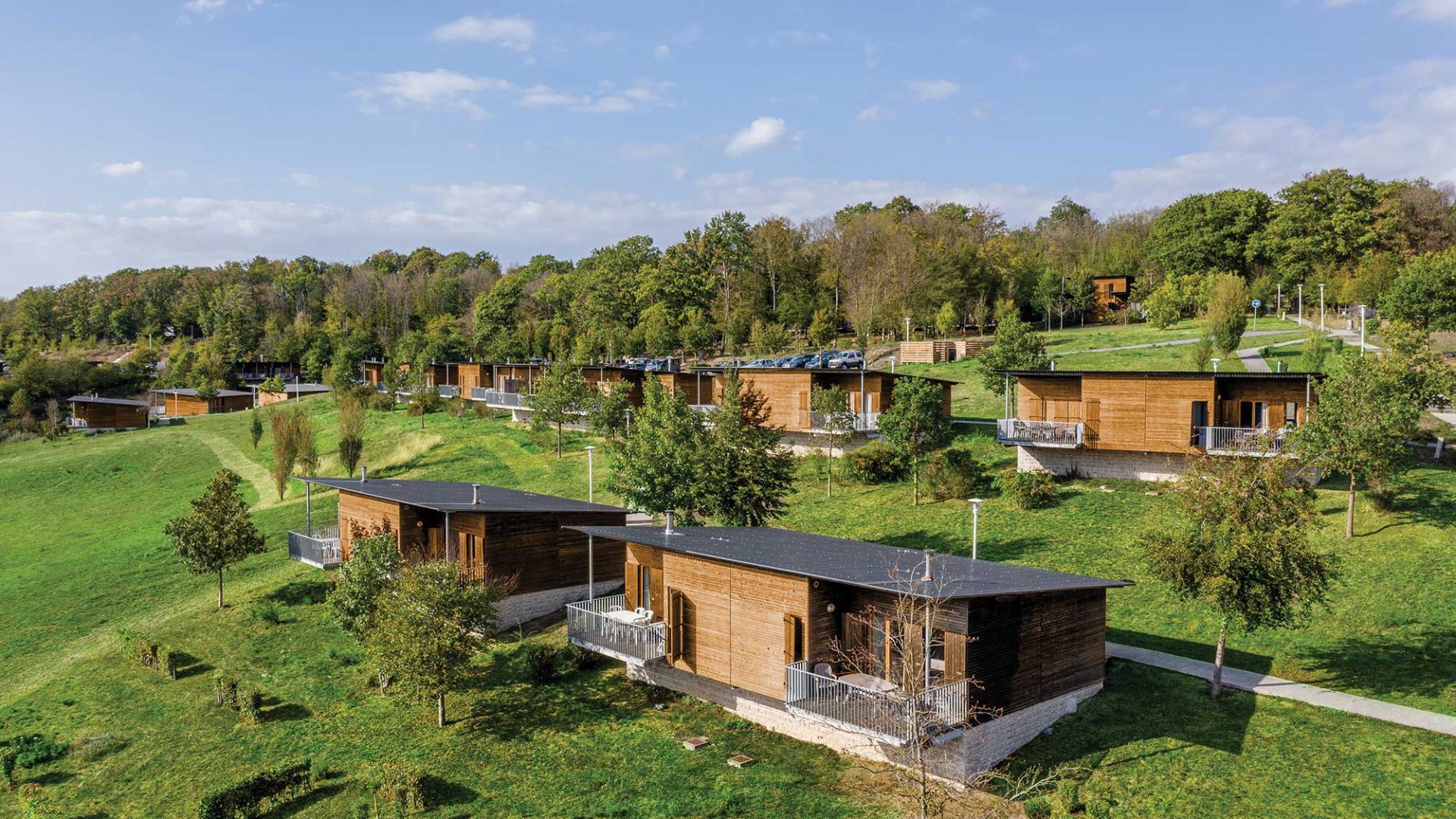 Vue aérienne des Cottages de Valjoly de Madame Vacances : résidence de chalets en pleine nature avec vue sur colline arborée